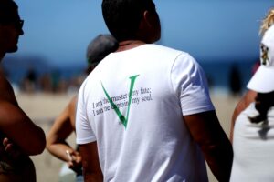 Back of athlete at the beach listening to his coach's workout brief.