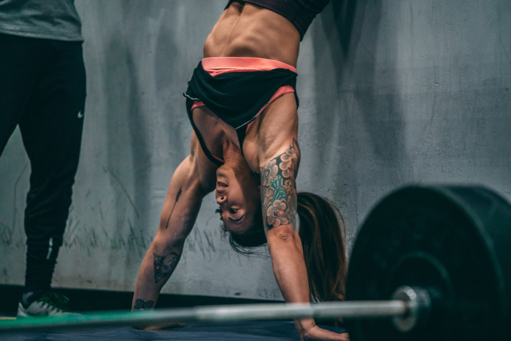 woman learns how to do a handstand push-up during a CrossFit workout