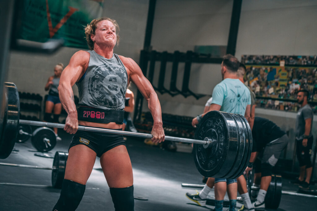 Invictus Athlete, Jenn Dancer, doing heavy cleans during a weightlifting session at the gym.