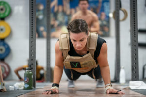 Female athlete wearing a weighted vest and doing push-ups.