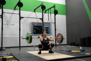 Male athlete wearing a singlet in the bottom on the lifting platform.