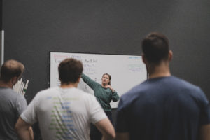 Female coach briefing her class at the whiteboard.