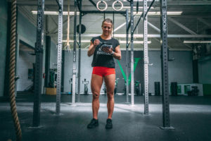 Female athlete eating a pre-made meal in an empty gym.