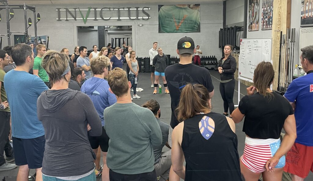 Group coaching members gathering around a white board listening to their coach brief the workout.