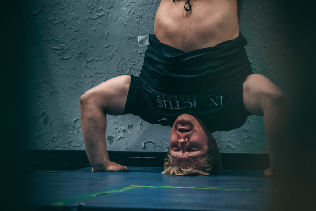 fitness coach shows how to do a handstand push-up against wall