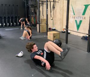 Two teen athletes doing dead bug holds.