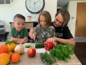 Three kids with better haircuts than most adults chopping veggies from their CSA box.