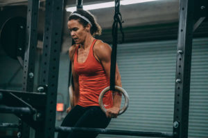 Female masters athlete at the top of a ring muscle-up