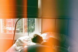 Man sleeping face down as the sunlight spills into his bedroom.