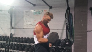 Invictus Athlete doing single-arm dumbbell curls.