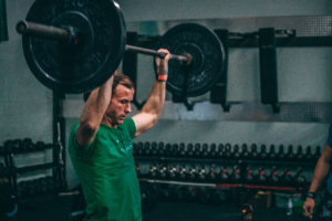 Male athlete bringing down the barbell from overhead.