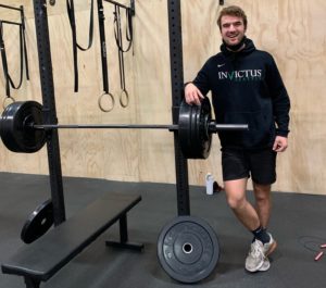 Male athlete posing next to his bench press bar.