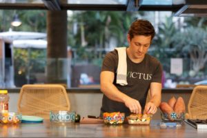 Male Invictus coach packs his Tupperware on the kitchen counter during his meal prep day.