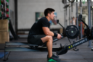 Athlete on rowing machine sitting and thinking.