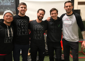 Group of athletes smiling with arms around each other.